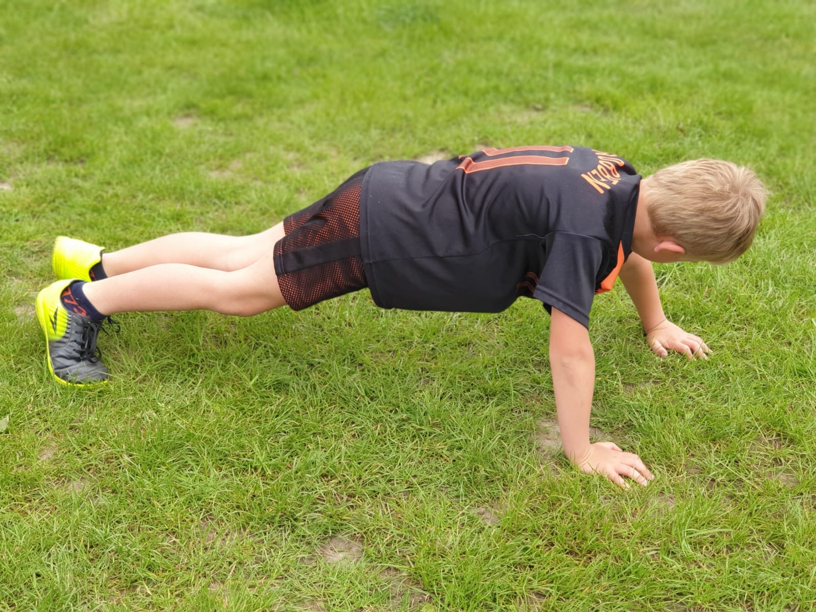 Beweging tijdens kindercoaching — een kind oefent buiten in het gras
